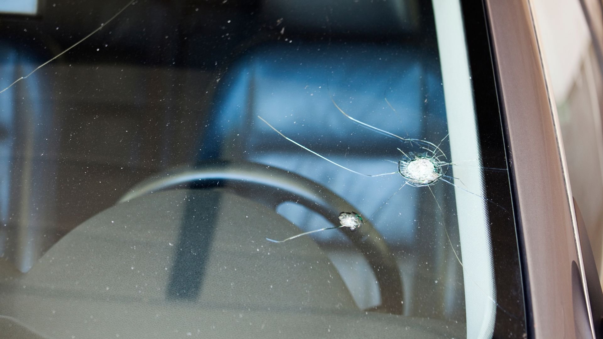Cracked car window with two bullet holes or impact points