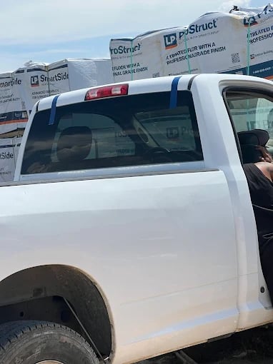 White pickup truck parked next to construction materials at work site