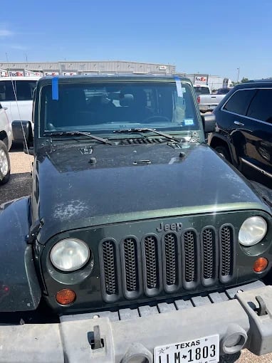 Dark green Jeep Wrangler parked in lot with Texas license plate