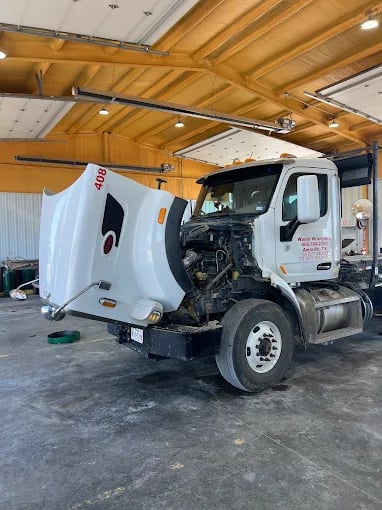 White service truck with open hood in maintenance garage