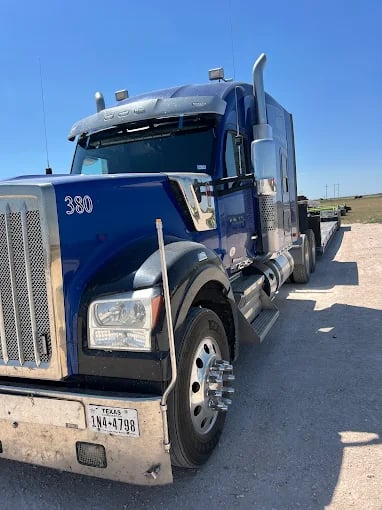 Blue semi-truck parked on gravel with Texas license plate